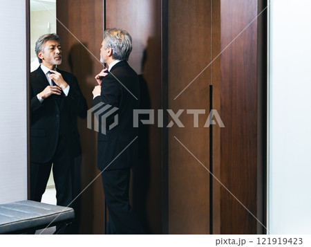 鏡を見て身だしなみを整えるミドル男性 鏡を見て身だしなみを整えるミドル男性 121919423