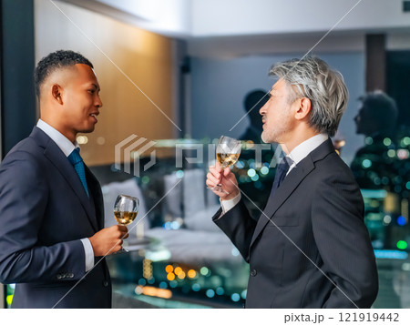 都市の夜景を背景に乾杯する多国籍ビジネスパーソン 121919442