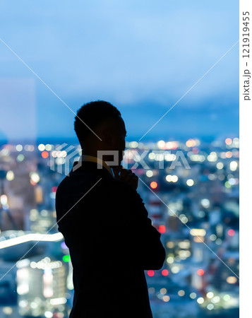 都市の夜景を背景に考えるビジネスパーソン 121919455