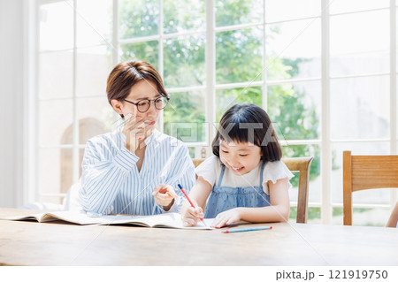 勉強する小学生の女の子に厳しい表情をする母親 121919750