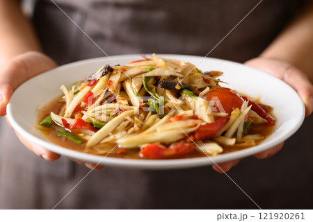 Spicy papaya salad (Som Tum) with hand, Local Thai food Spicy papaya salad (Som Tum) with hand, Local Thai food 121920261
