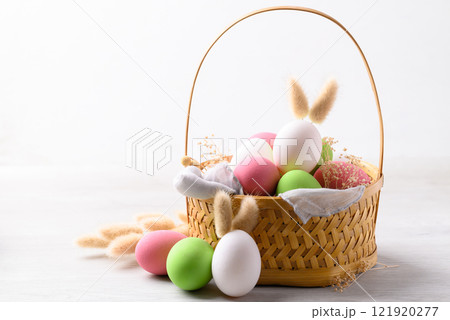 Easter eggs with bunny rabbit ears in basket on white background Easter eggs with bunny rabbit ears in basket on white background 121920277