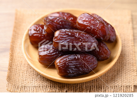 Date palm fruit (MedJool) on wooden plate 121920285