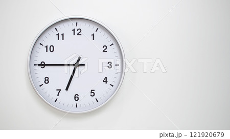 Minimalist White Clock with Silver Frame Striking 18.45/06.45 on White Background. Perfect for Time Management and Corporate Campaigns 121920679