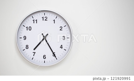 Minimalist White Clock with Silver Frame Striking 19.25/07.25 on White Background. Perfect for Time Management and Corporate Campaigns Minimalist White Clock with Silver Frame Striking 19.25/07.25 on White Background. Perfect for Time Management and Corporate Campaigns 121920991