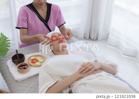 Relaxed young asian woman getting eye nature treatment by tomato at spa salon. Wellness and healing concept. 121921036