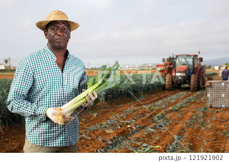 Portrait of positive farmer with crate of fresh leek 121921902