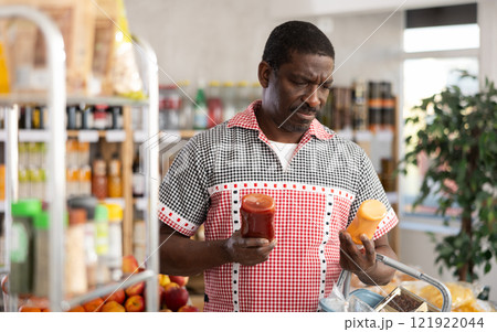 Adult man choosing ketchup or mustard at grocery 121922044