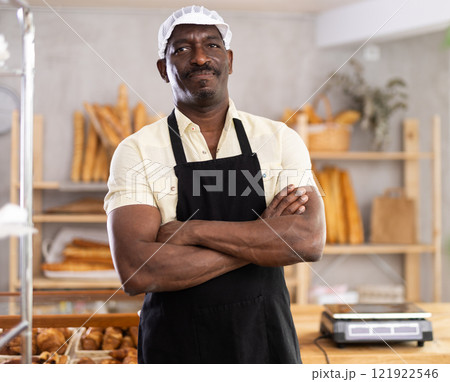 Portrait of professional smiling male baker in uniform in bakery 121922546
