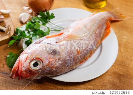 Raw whole red palometa fish with garlic and parsley on desk 121922658