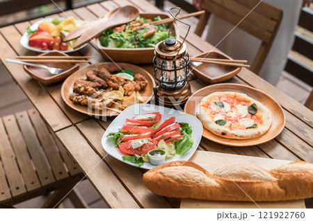 ウッドデッキのテーブルに並んだホームパーティー・グランピングの豪華な洋食・料理 121922760