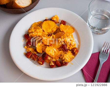 Huevos con chistorra - fried eggs with sausages served with potatoes closeup Huevos con chistorra - fried eggs with sausages served with potatoes closeup 121922866