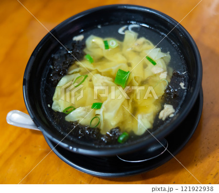 Wonton soup is cooked dumplings filled with meat or seafood. They are served in broth, usually enriched with onions and other ingredients. Chinese cuisine 121922938