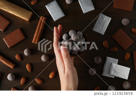 Chocolate balls in a wooden bowl with chocolate bars and almonds 121923659
