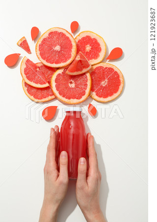 Grapefruit slices and bottle of juice in female hands on white background, top view Grapefruit slices and bottle of juice in female hands on white background, top view 121923687