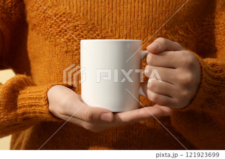 A woman holds a white cup in her hands A woman holds a white cup in her hands 121923699