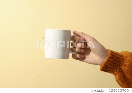A woman holds a white cup in her hands A woman holds a white cup in her hands 121923700