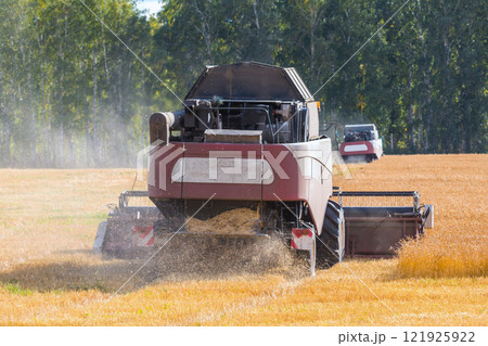 Modern combine harvesters working in the field on a clear sunny day 121925922
