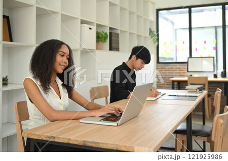 Young businesspeople concentrating on their tasks in a shared office space 121925986