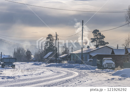 A beautiful winter village scene showcasing snowcovered roads along with billowing smoke A beautiful winter village scene showcasing snowcovered roads along with billowing smoke 121926292