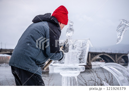 The author of the sculptor makes ice sculpture elements, in winter on the street in the center near the bridge over the Yenisei River Krasnoyarsk, 121926379