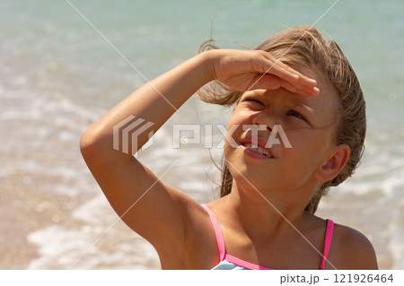 Beautiful caucasian child of 7-8 years looking at sun and covering face with hand 121926464