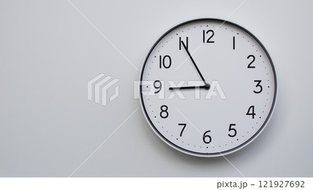 Minimalist Analog Wall Clock with White Face and Simple Black Hands Showing 20.55/08.55 - Ideal for Time Management and Modern Decor Concepts Minimalist Analog Wall Clock with White Face and Simple Black Hands Showing 20.55/08.55 - Ideal for Time Management and Modern Decor Concepts 121927692