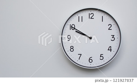 Minimalist Analog Wall Clock with White Face and Simple Black Hands Showing 21.50/09.50 - Ideal for Time Management and Modern Decor Concepts Minimalist Analog Wall Clock with White Face and Simple Black Hands Showing 21.50/09.50 - Ideal for Time Management and Modern Decor Concepts 121927837