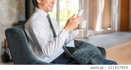 家でスマホ・スマートフォンを見るビジネスマン（ニュース・電子書籍・読書・アプリ・スケジュール） 121927924