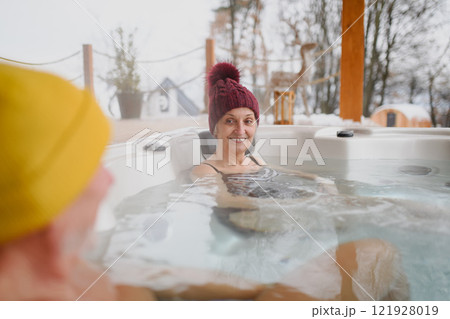 Senior couple bathing in hot tub during cold winter day. Romantic wellness getaway with spa during Valentine's weekend. Senior couple bathing in hot tub during cold winter day. Romantic wellness getaway with spa during Valentine's weekend. 121928019