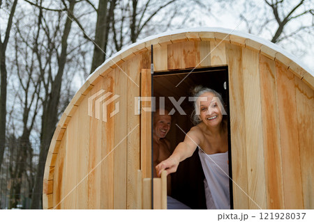 Senior woman entering small sauna. Winter spa weekend getaway for elderly people. 121928037