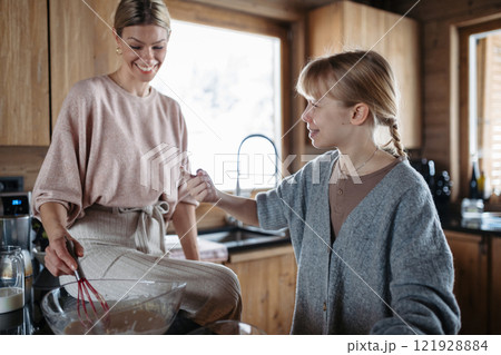 Mom and daughter making pancakes for breakfast. Girl mixing, preparing pancake batter in the kitchen. Mom and daughter making pancakes for breakfast. Girl mixing, preparing pancake batter in the kitchen. 121928884