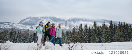 Family walking across snowy winter nature, holding by hands. Family winter vacation in snowy mountains. Banner with copy space. Family walking across snowy winter nature, holding by hands. Family winter vacation in snowy mountains. Banner with copy space. 121928921