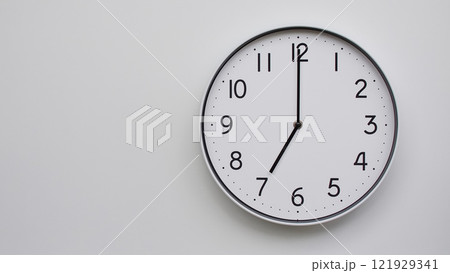 Minimalist Analog Wall Clock with White Face and Simple Black Hands Showing 19.00/07.00 - Ideal for Time Management and Modern Decor Concepts 121929341