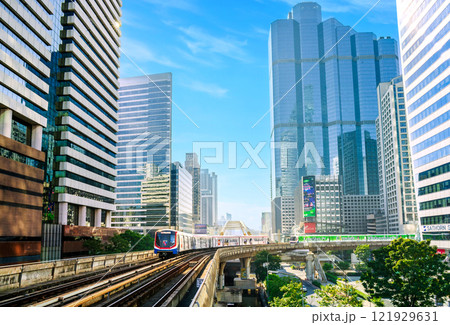 BTS Skytrain passing through Sathorn Skywalk, surrounded by skyscrapers and modern architecture, symbolizing urban transportation and business. 121929631