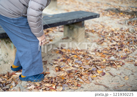 公園のベンチから立ち上がった膝の痛そうなシニア女性 121930225