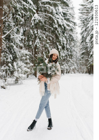 Happy woman is posing in the snow with bouquet of flowers cotton in forest Happy woman is posing in the snow with bouquet of flowers cotton in forest 121930613