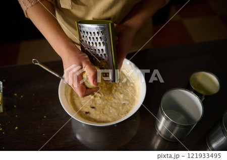 Close-up of Person Grating Ingredients for a Recipe in the Kitchen 121933495
