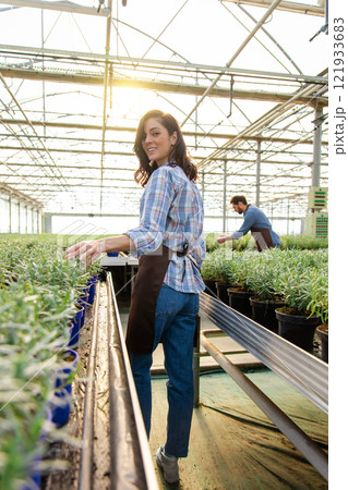 Smiling pretty female glasshouse worker at her working place 121933683