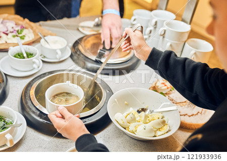 A man pours delicious soup from a large pot into a bowl. Buffet in the restaurant. With space to copy. High quality photo 121933936