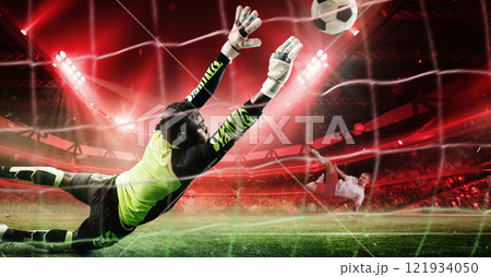 Goalkeeper in vibrant neon uniform diving mid-air to block powerful penalty shot during intense soccer game in 3D stadium filled with dramatic red lighting. 121934050