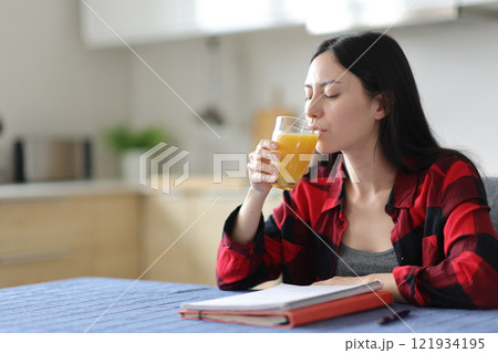 Asian student drinking orange juice in the kitchen 121934195