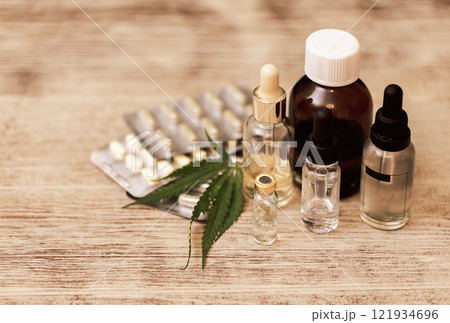 Mockups of medicines on a beige background with cannabis leaves. Layouts of a medicine bottle and a white empty spray bottle and pills on a marble table with green hemp leaves. Mockups of medicines on a beige background with cannabis leaves. Layouts of a medicine bottle and a white empty spray bottle and pills on a marble table with green hemp leaves. 121934696