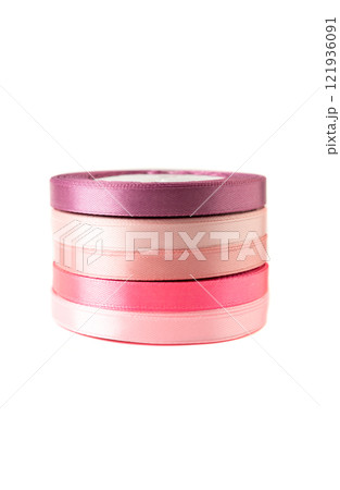 stack of satin ribbons in shades of pink against a white background 121936091