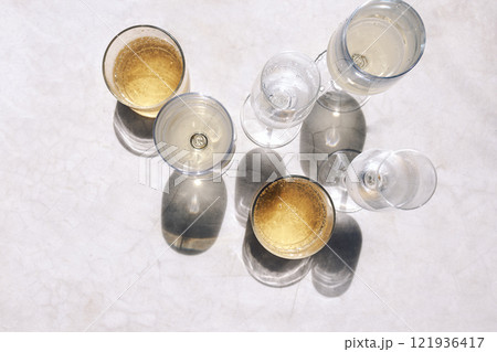 Glasses with various chilled alcoholic beverages on the marble table. Top view. Mineral water and champagne. Fragrant sparkling wines in bright sunlight. Glasses with various chilled alcoholic beverages on the marble table. Top view. Mineral water and champagne. Fragrant sparkling wines in bright sunlight. 121936417