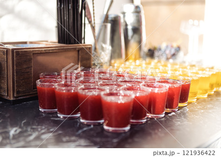 Smooth rows of glasses with delicious refreshing berry and fruit drinks. Fresh fragrant cocktails on the bar counter. Orange and raspberry juice on a buffet. Smooth rows of glasses with delicious refreshing berry and fruit drinks. Fresh fragrant cocktails on the bar counter. Orange and raspberry juice on a buffet. 121936422
