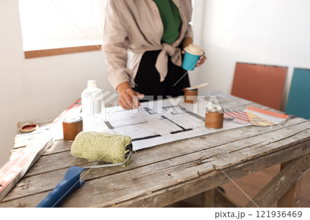 Attractive smiling African woman holds tablet and coffee and checks house plan 121936469