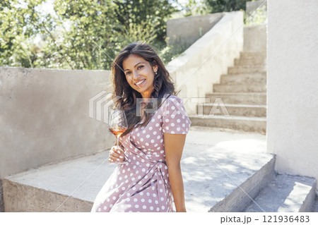 Beautiful young mixed race woman in pink dress smiling and holding glass of champagne. Beautiful young mixed race woman in pink dress smiling and holding glass of champagne. 121936483