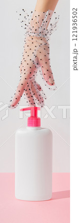 Womans hand touch white bottle on pastel pink and white background. Self care concept Womans hand touch white bottle on pastel pink and white background. Self care concept 121936502