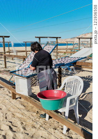 Portugese woman drying fish on the beach. Traditional portuguese food snacks 121936508